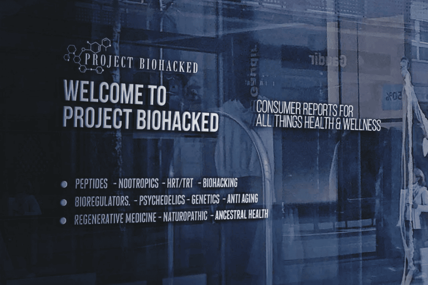  Sign on a glass window reads "Welcome to Project Biohacked" with topics like peptides, nootropics, HRT/TRT, psychedelics, and anti-aging listed underneath